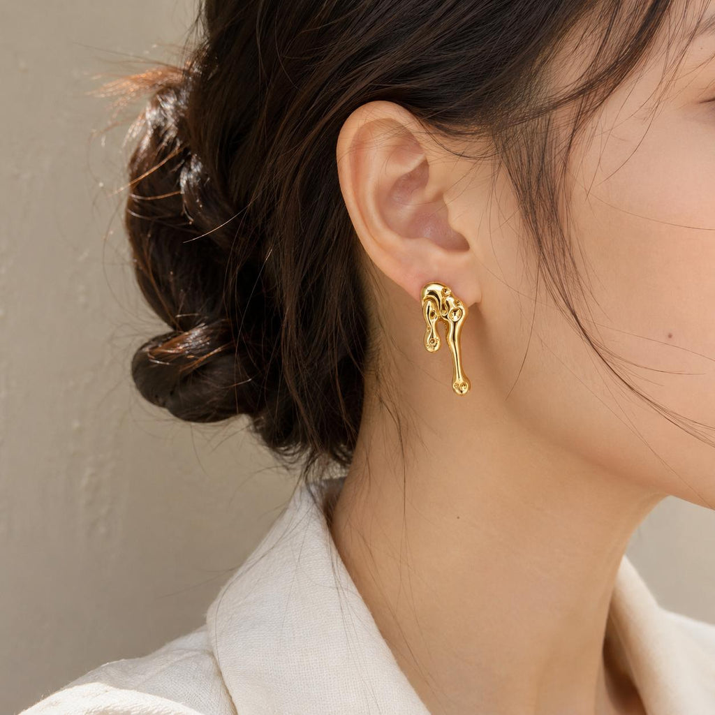 Aretes largos dorados de diseño abstracto con efecto metal líquido para mujer