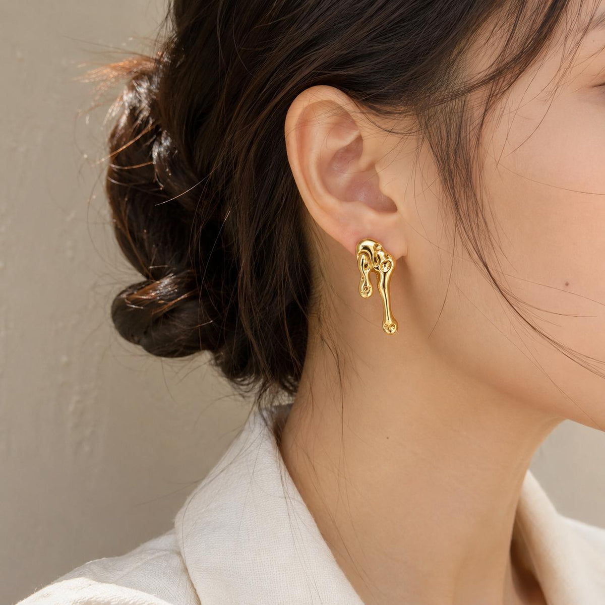Aretes largos dorados de diseño abstracto con efecto metal líquido para mujer