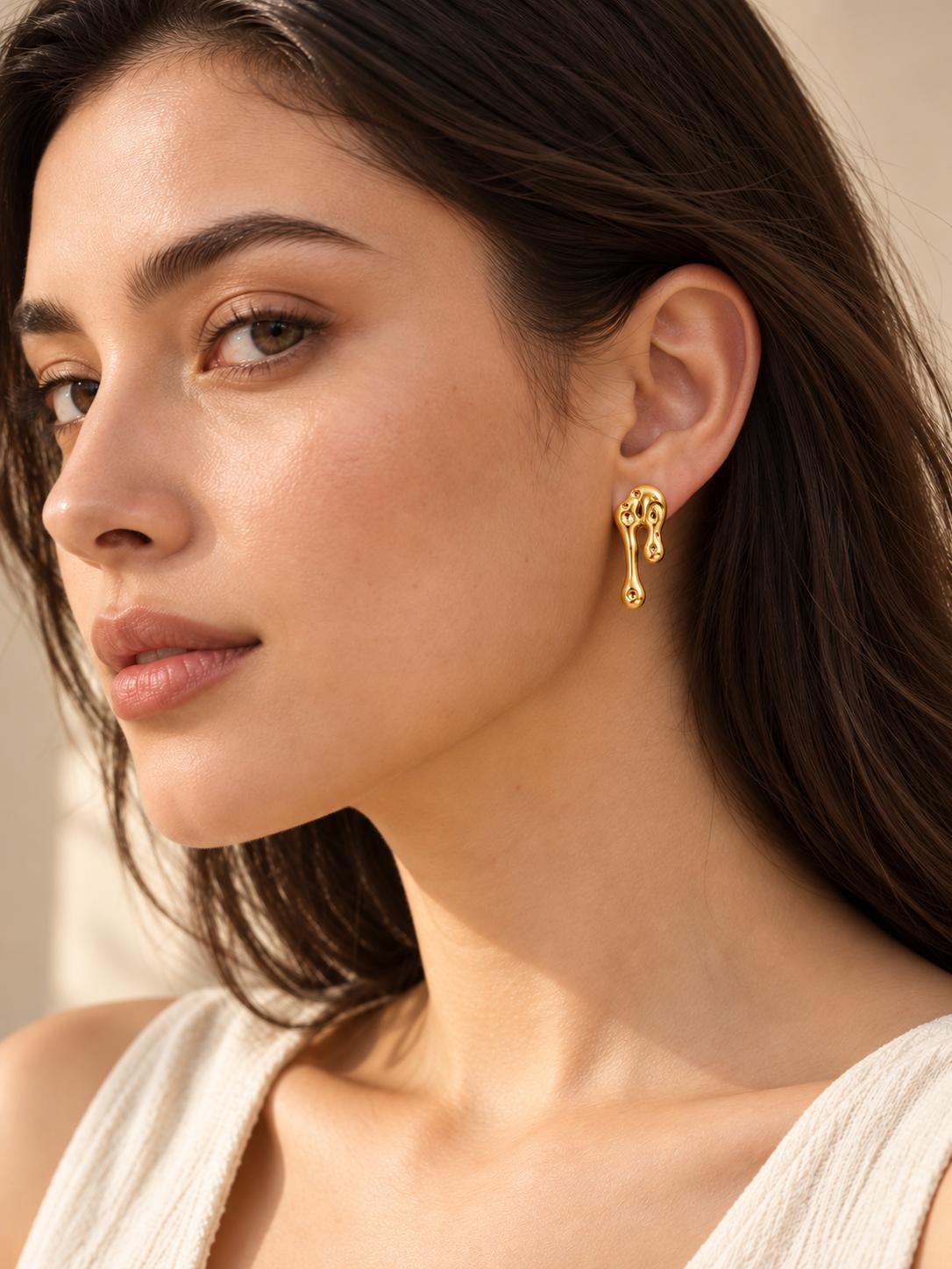 Aretes largos dorados de diseño abstracto con efecto metal líquido para mujer